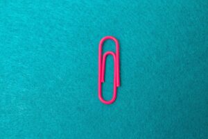 a pink paper clip sitting on top of a blue surface