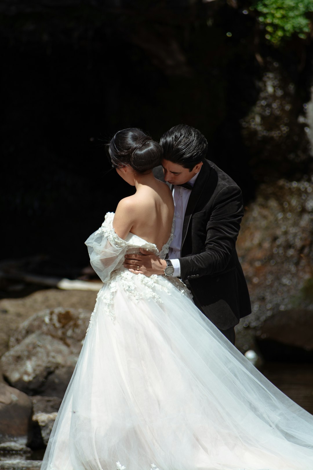 Photo by Fotógrafo Samuel Cruz Groom kisses bride's shoulder near waterfall